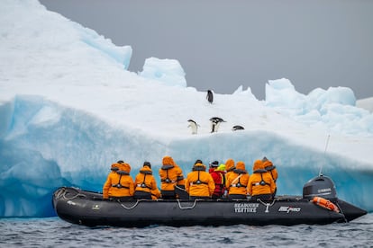 Un grupo de turistas a bordo de una zódiac observan pingüinos en la Antártida.