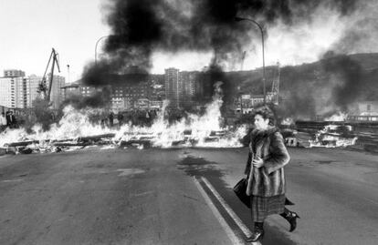 Una mujer pasa delante de las barricadas con que los trabajadores de Euskalduna se enfrentan con la polica en Bilbao.