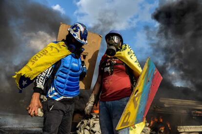 Dos activistas de la oposición venezolana ataviados con cascos y máscaras durante las protestas.