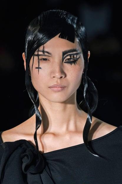 Yohji Yamamoto se marca uno de los maquillajes más oscuros de la pasarela. Trazos negros y cruces invertidas que son muy fáciles de copiar con ayuda de un lápiz o eyeliner negro.