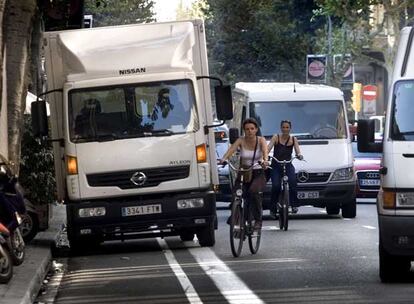 Dos ciclistas tienen que sortear un camión estacionado en el carril bici en medio de un denso tráfico en la calle del Consell de Cent.