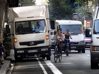 Dos ciclistas tienen que sortear un camión estacionado en el carril bici en medio de un denso tráfico en la calle del Consell de Cent.
