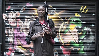 Cheikh Fayé, con una gaita, frente a un grafiti, en Galicia.