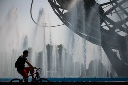 Un hombre en bicicleta observa las fuentes de agua en el parque Flushing Meadows-Corona, Nueva York, el 22 de agosto de 2017. 