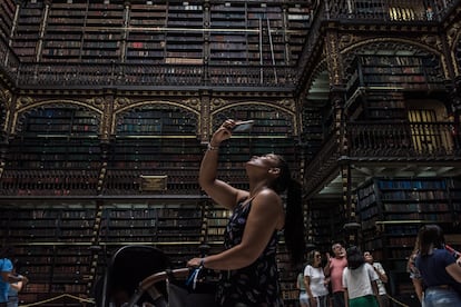 Visitantes y turistas fotografían el salón principal del Real Gabinete Português de Leitura.