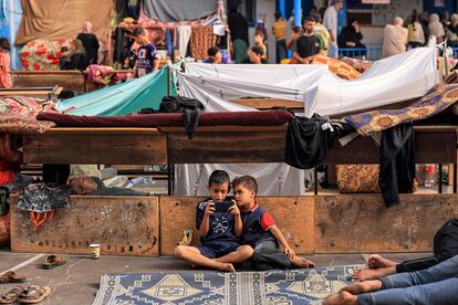 Dos niños se entretienen jugando con un teléfono móvil en el patio de una escuela de Naciones Unidas, en Jan Yunis, al sur de la franja de Gaza, este miércoles.