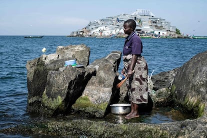 Una mujer limpia algunos artículos sobre unas rocas en la isla de Usingo, frente al territorio de Migingo.