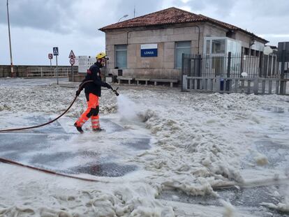 Un trabajador retira la espuma producida por el fuerte oleaje este viernes en A Guarda (Pontevedra).