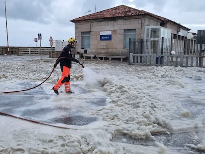 Un trabajador retira la espuma producida por el fuerte oleaje este viernes en A Guarda (Pontevedra).