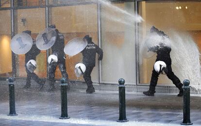 Policías se protegen de la leche con sus escudos.