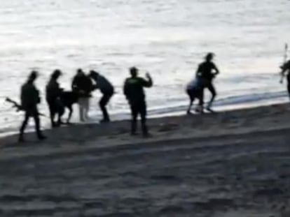 Civil Guard officers return undocumented migrants to Morocco at Tarajal beach.