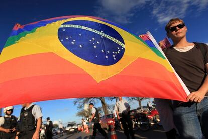 A gay activist carries a Brazil flag in rainbow colours in protest at the "March For Family" demonstration against abortion and gay marriage, in front of the National Congress in Brasilia