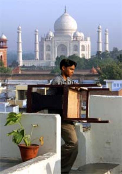 Un joven lleva una silla a un turístico hotel cercano al famoso monumento.