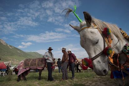 Jinetes nómadas tibetanos tras sus caballos, preparándose para una carrera en la meseta del Tíbet, en el condado de Yushu (China).