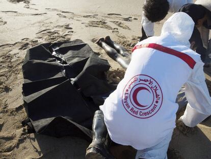 Voluntarios de la Media Luna Roja retiran el cadáver de un inmigrante llegado a una playa de Trípoli.