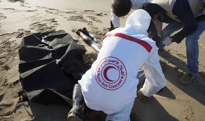 Voluntarios de la Media Luna Roja retiran el cadver de un inmigrante llegado a una playa de Trpoli.