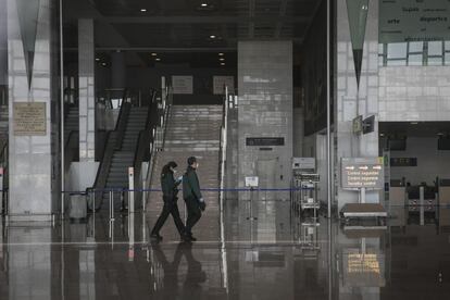 Dos trabajadores recorren la Terminal 2 del aeropuerto de El Prat una vez cerrada tras la cancelación masiva de vuelos.