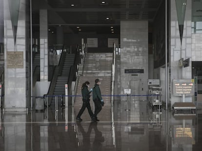 Dos trabajadores recorren la Terminal 2 del aeropuerto de El Prat una vez cerrada tras la cancelación masiva de vuelos.