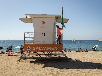 Un socorrista levanta la bandera verde en una de las torretas de vigilancia de la playa de Nova Icària de Barcelona