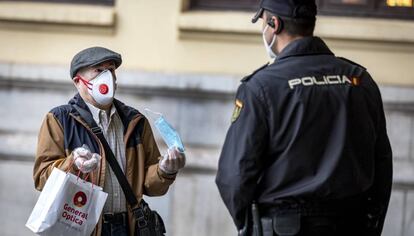 Un hombre muestra una mascarilla a un policía en la estación de Renfe de Valencia.