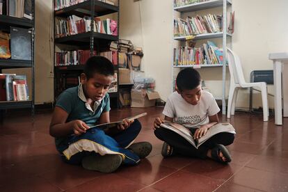 Dos niños leen cuentos en la biblioteca de la vereda Monterredondo, en la Zona Rural Alta Miranda (Departamento de Cauca).