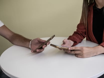 Dos jóvenes consultan sus teléfonos móviles.