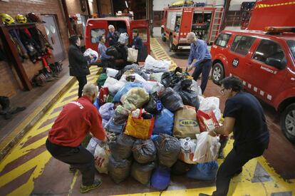 Unos bomberos de Terrassa trasladan ropa a una de las furgonetas.