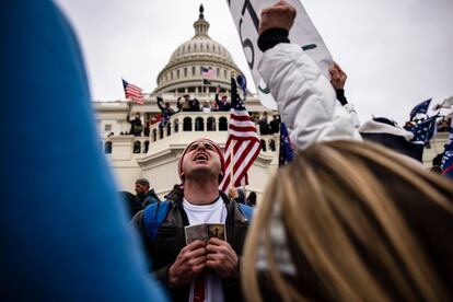 Un hombre reza en el exterior del Capitolio durante el asalto del 6 de enero, en Washington.