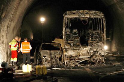 Varios agentes inspeccionan los restos calcinados de un coche y un autobús en el interior del tunel Viamala, cerca de Thusis, al sudeste de Suiza.