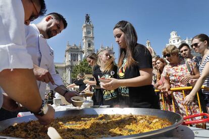 Azafatas del evento preparan los platos para servir a los comensales en la plaza del Ayuntamiento de Valencia.