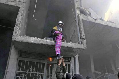 Un miembro de la Defensa Civil Siria rescata a una niña después de los ataques realizados en la región de Guta Oriental por fuerzas del gobierno sirio.