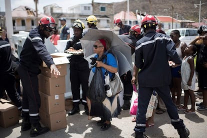 En la imagen, una mujer espera recibir comida por parte de bomberos franceses, en Sandy Ground, en San Martín.