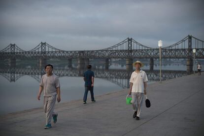 Pessoas caminham próximo à Ponte da Amizade Sinocoreana, que liga a Coreia do Norte à China, na cidade chinesa de Dandong.