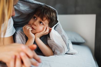 A young mother and her 7-year-old son are having a cuddle time in bed.