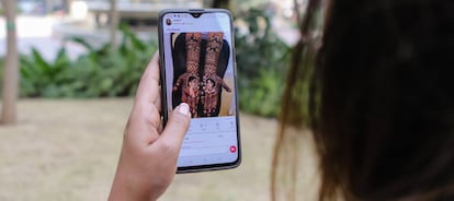 Una joven mira a través de ShareChat los diseños con pintura de henna para tatuajes temporales disponible en la aplicación.