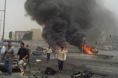 Varias personas caminan entre los restos de un coche bomba ayer en Bagdad.