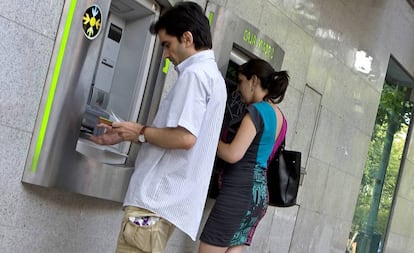 Dos clientes sacan dinero en sendos cajeros en la calle de Alcalá de Madrid.