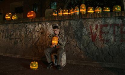 Un niño vende calabazas con velas en el interior en una calle de Tirana en un día antes de Halloween.