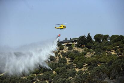 Un helicóptero lanza agua a una de las zonas afectadas por el incendi forestal en la sierra oeste de Madrid. Los 2.000 vecinos de Valdemorillo desalojados ayer han regresado a sus casas esta mañana, durante la cual el operativo de extinción ha declarado bajo control el fuego, cuyo perímetro final abarca entre 600 y 700 hectáreas.