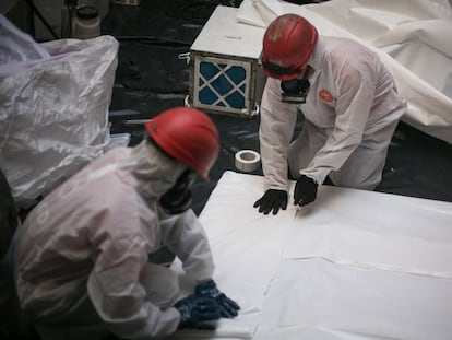 Operarios con equipos de protección trabajan en la retirada de pizarras con amianto, en Barcelona en 2019.
