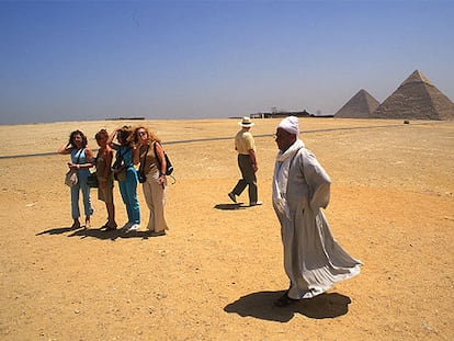 Un grupo de turistas en la meseta de Guiza, en El Cairo, con las pirámides de Kefrén, que aún conserva parte del revestimiento de caliza blanca, y Keops.