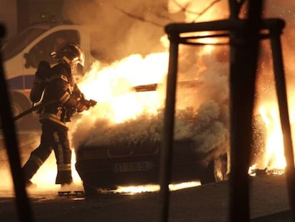 Un bombero intenta apagar el incendio en un coche en Nochevieja en Estrasburgo.