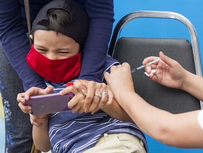 Un niño es distraído mientras le aplican una vacuna.