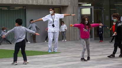 La enfermera Naiara indica a alumnos de Primaria cómo tiene que extender los brazos en el patio de recreo para mantener la distancia entre ellos.