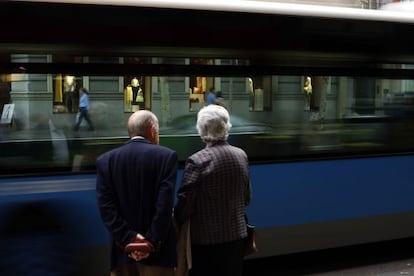 Una pareja de jubilados mira un autob&uacute;s pasar en una calle de Madrid