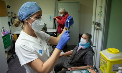 Una enfermera se dispone a inyectar la primera dosis de la vacuna contra la covid a una anciana en Barcelona. 
 