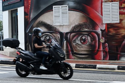 Un motociclista pasa junto a un mural en una pared en Singapur.