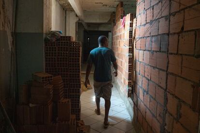 Los habitantes de las ocupaciones urbanas suelen recurrir al llamado 'mutirão', una forma de trabajo colectivo para construir las viviendas. En la foto, un vecino pasa por una vivienda en proceso de construcción, donde las paredes de ladrillo sirven para delimitar los espacios.