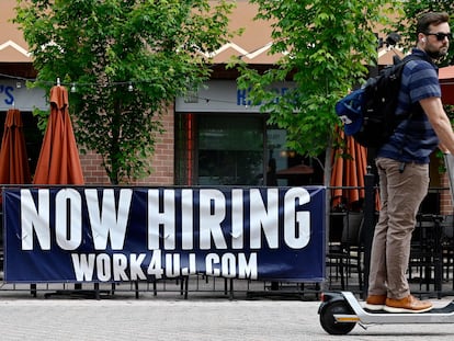 A man passes in front of a "now hiring" sign posted outside a restaurant in Arlington, Virginia, in June 2022.