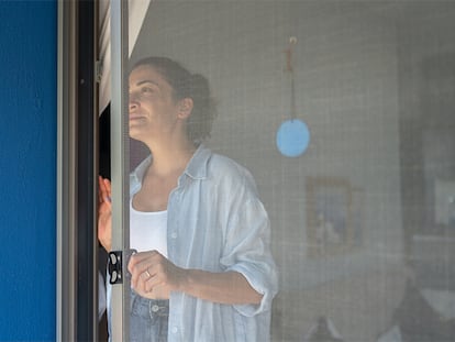Una chica abriendo la mosquitera de su terraza.